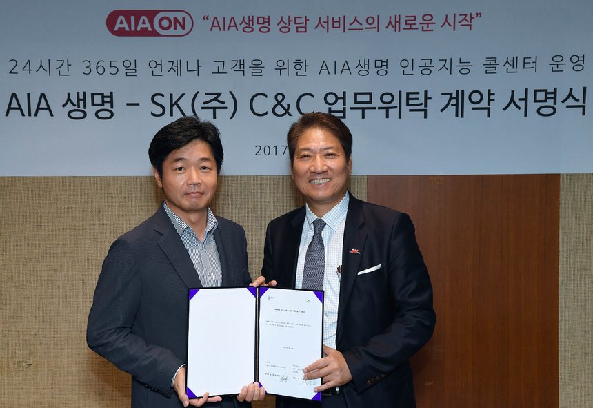 이기열 SK C&C ITS 사업장(왼쪽)과 김대일AIA생명 운영본부장(오른쪽)이 인공지능 콜센터 서비스를 위한 AIA생명 고객서비스 업무 위탁 사업 계약 체결 후 기념 사진을 촬영하고 있다。